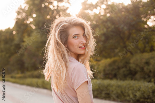 Portrait of happy beautiful young woman in the city under sunlight. Turn around