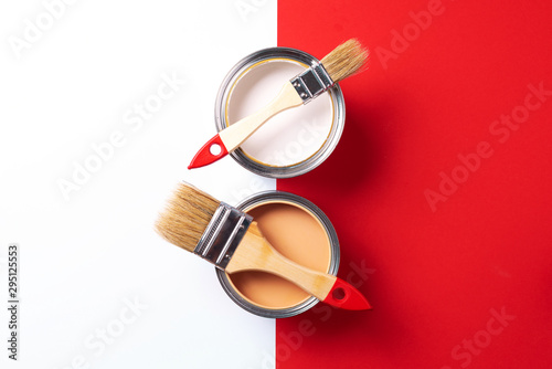 Fototapeta Naklejka Na Ścianę i Meble -  Wooden paint brushes, open paint cans on trendy red and white background. Top view, copy space. Appartment renovation, repair, building and home design concept.