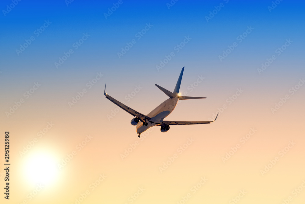 Modern airplane flying against sunset sky background Passenger aircraft landing at sunrise Commercial plane taking off towards setting sun Business jet arriving with landing gear down Aerial view Modern airplane flying against sunset sky background Passenger aircraft landing at sunrise Commercial plane taking off towards setting sun Business jet arriving with landing gear down Aerial view