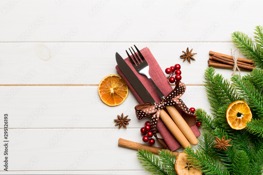 Top view of utensils on festive napkin on wooden background. Christmas decorations with dried fruits and cinnamon. New year dinner concept with copy space Top view of utensils on festive napkin on wooden background. Christmas decorations with dried fruits and cinnamon. New year dinner concept with copy space