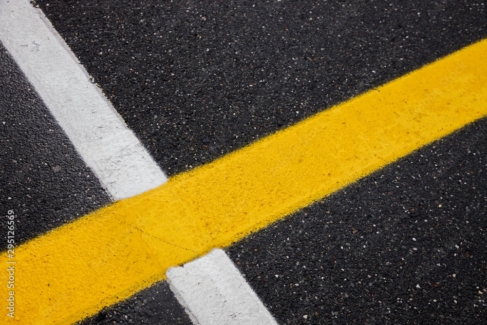 white and yellow lines on a black asphalt, background with painted marks for motor racing, space for text white and yellow lines on a black asphalt, background with painted marks for motor racing, space for text