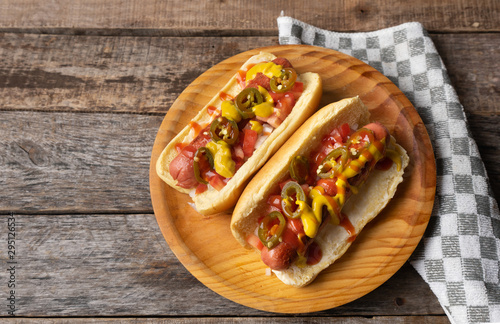 Hot dog with jalapeno pepper and tomato on wooden background