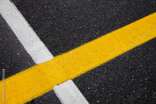 white and yellow lines on a black asphalt, background with painted marks for motor racing, space for text © YK