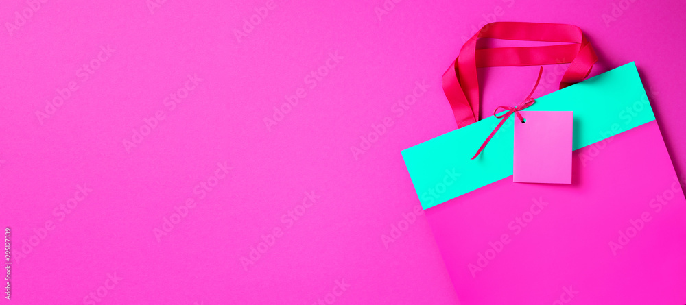 Pink and turquoise paper shopping bag on trendy green background. Top view, copy space. Gift concept. Woman's day. Valentine's day. Ready for birthday party.