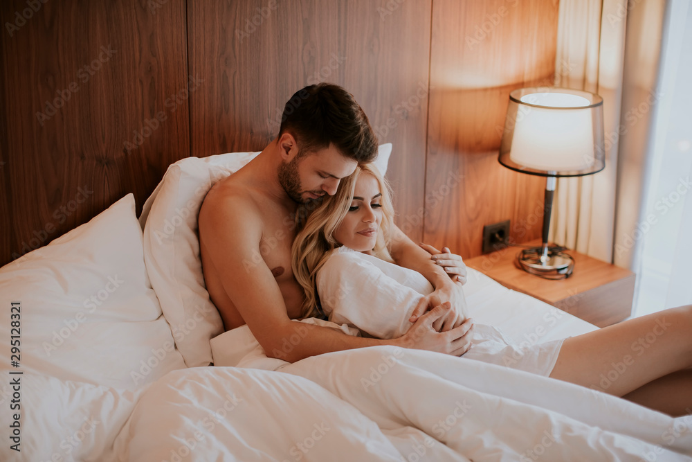 Lovely couple hugging on their bed at home Lovely couple hugging on their bed at home