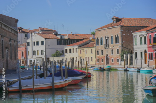 Murano Island, Venice. Buildings, canal, boats at the quays, general plan