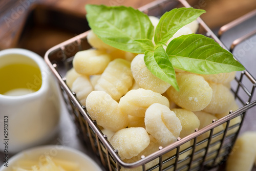 Close-up of raw potato gnocchi with fresh green basil leaves, selective focus