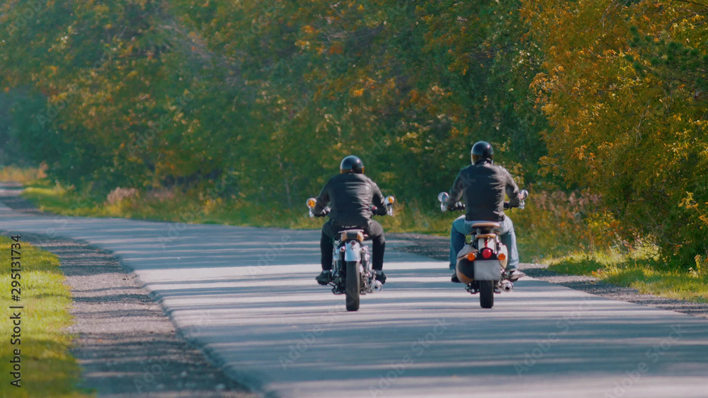 Obraz premium Bikers are riding on the road in the forest near each other