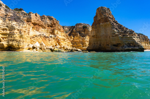 Turquoise sea waters and the sandstone cliffs of Praia da Marinha seen from a boat, Lagoa, Algarve, Portugal
