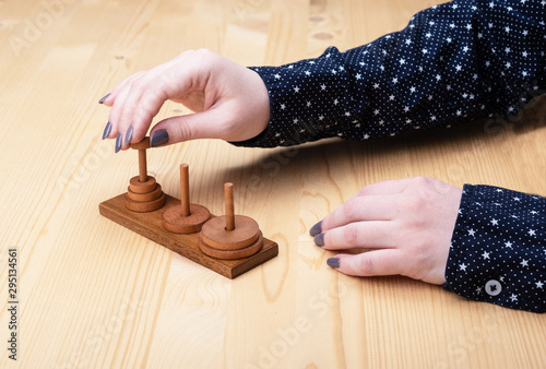 A girl is trying to assemble a puzzle tower of hanoi.