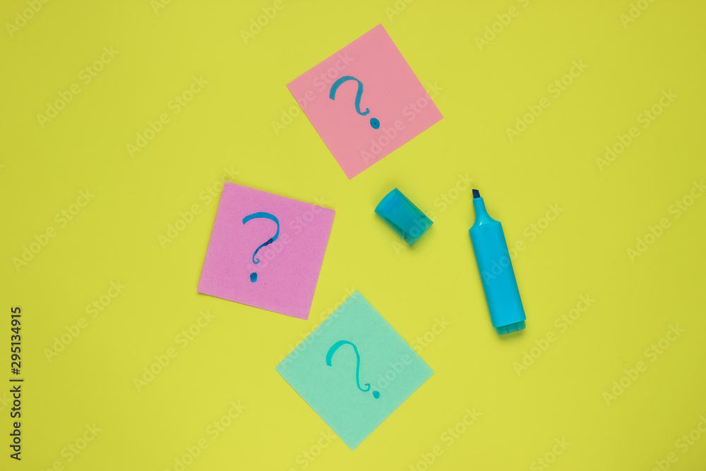 Memo pieces of paper with drawn question marks, felt-tip pen on green background. Top view