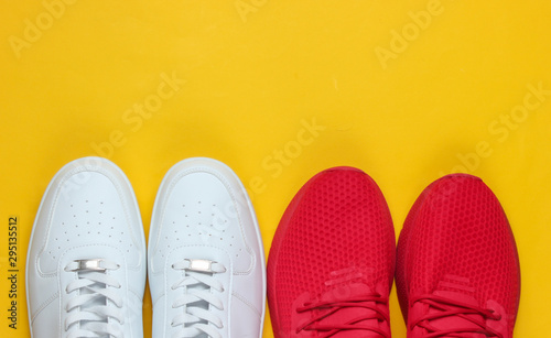 Two pairs of sneakers on a yellow background. White and red shoes. Top view