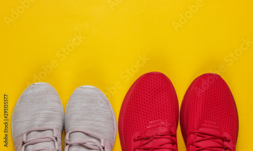 Two pairs of women's and men's sports shoes for running on a yellow background. Concept of couple doing sports.
