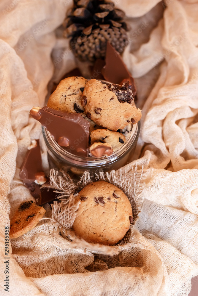 Fototapeta premium Shortbread chocolate cookies and a glass of milk on a brown background. Milk chocolate with nuts and cookies.