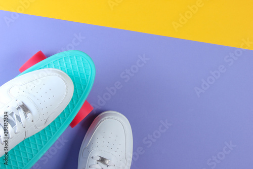 White sneakers on plastic mini cruiser board. Pastel color background. Top view