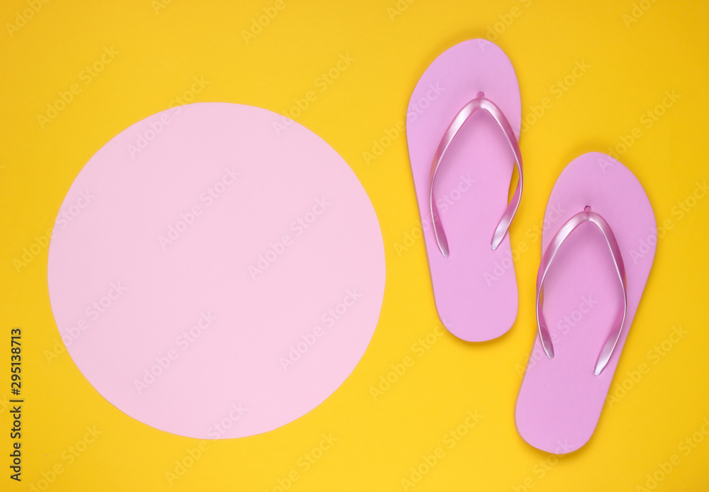 Pink flip flops on yellow background with pink pastel circle for copy space. Minimalistic vacation on the beach concept. Summer time