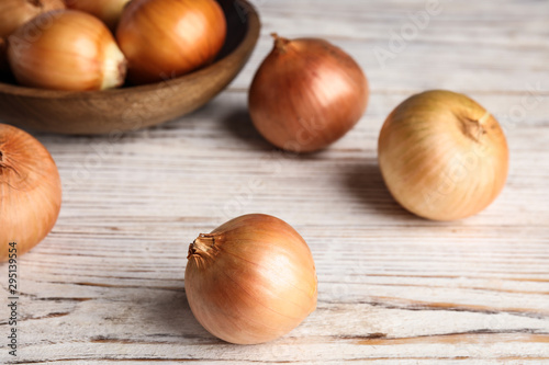 Ripe onions on white wooden table, closeup