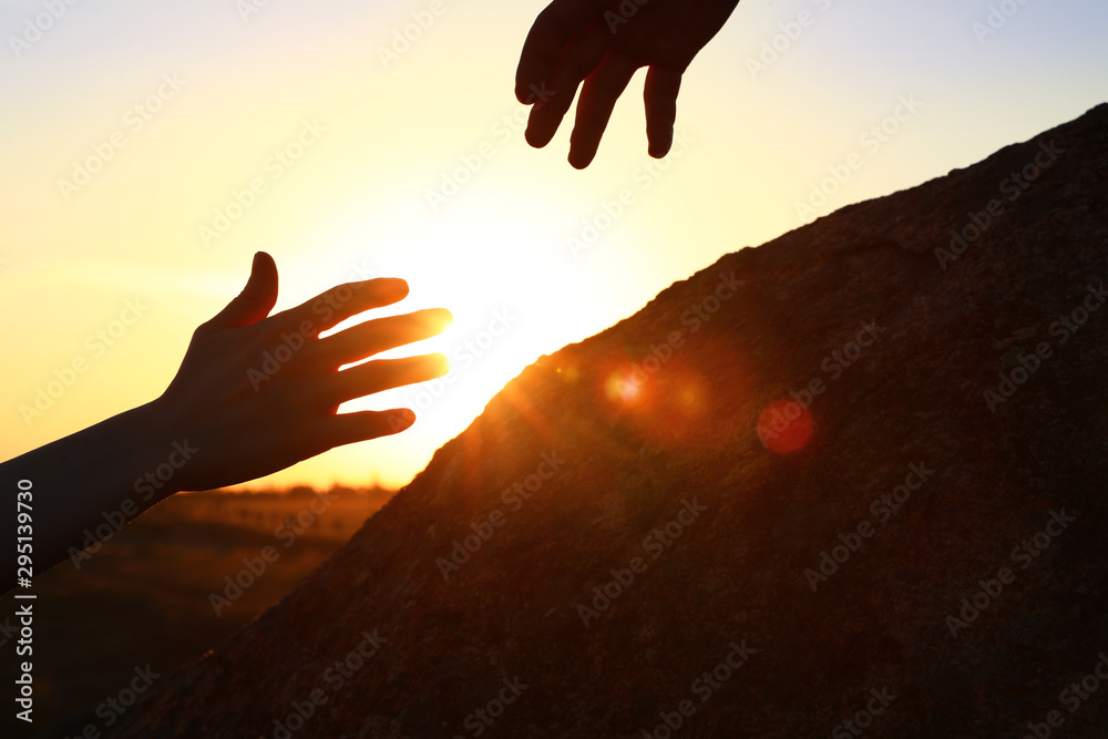 Hiker helping friend outdoors at sunset. Help and support concept Hiker helping friend outdoors at sunset. Help and support concept