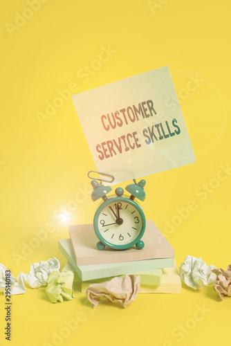 Text sign showing Customer Service Skills. Business photo showcasing Aptitude to master to improve dealings with client Alarm clock sticky note paper balls stacked notepads colored background photo