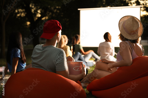 Fotografie Young couple with popcorn watching movie in open air cinema