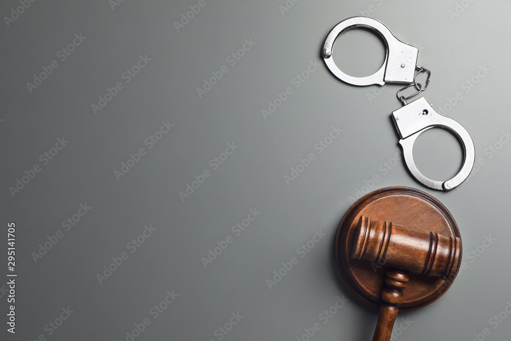 Judge's gavel and handcuffs on grey background, flat lay with space for text. Criminal law concept Judge's gavel and handcuffs on grey background, flat lay with space for text. Criminal law concept