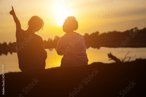 Mother encouraged her son outdoors at sunset  silhouette concept