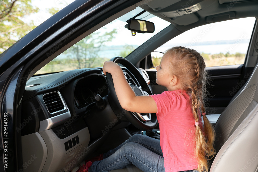 Little girl playing with steering wheel in car. Family trip Little girl playing with steering wheel in car. Family trip