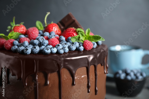 Freshly made tasty chocolate cake decorated with berries on table  closeup