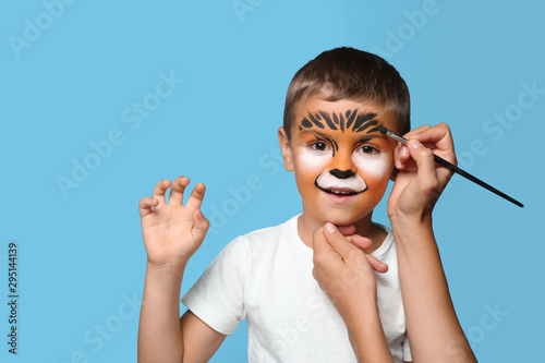 Obraz na plátně Artist painting face of little boy on blue background