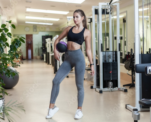 Functional Training Concept. Young fit woman in sportswear posing with medicine ball in the gym