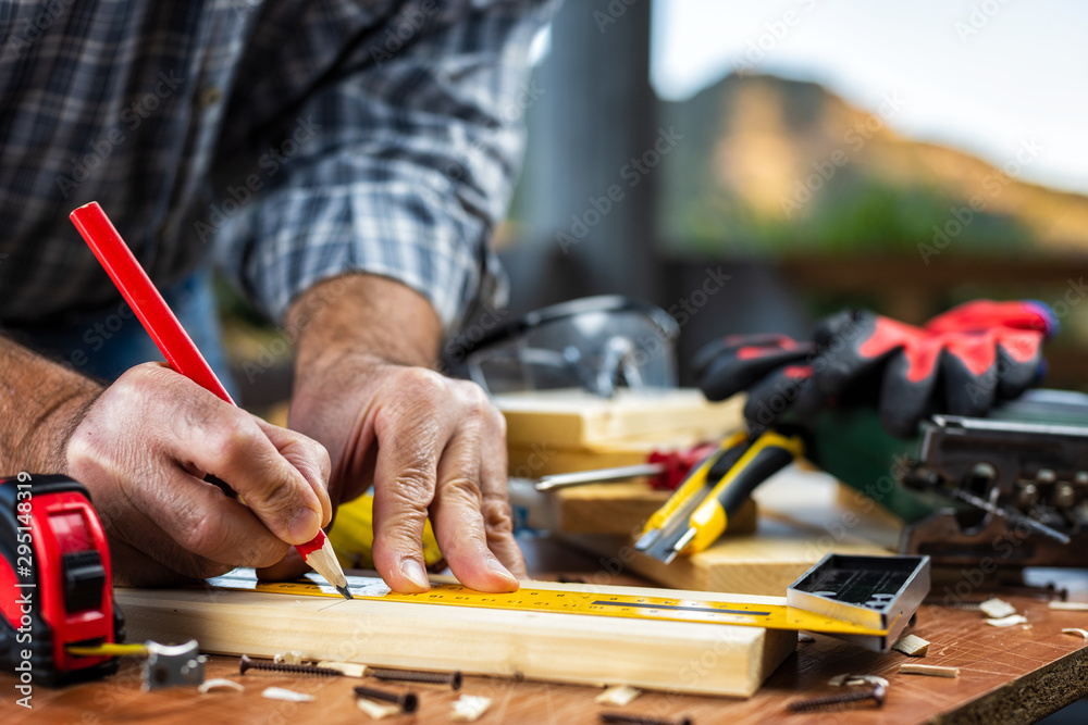 Adult carpenter craftsman with a pencil and the carpenter's square trace the cutting line on a wooden table. Construction industry, housework do it yourself. Stock photography. Adult carpenter craftsman with a pencil and the carpenter's square trace the cutting line on a wooden table. Construction industry, housework do it yourself. Stock photography.