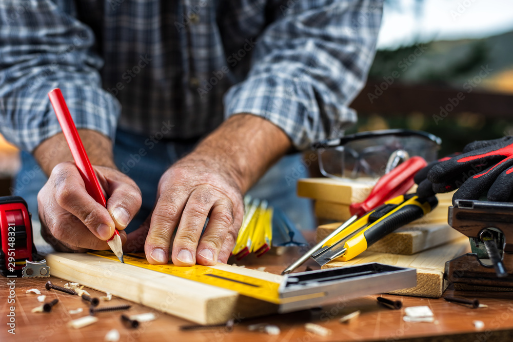 Adult carpenter craftsman with a pencil and the carpenter's square trace the cutting line on a wooden table. Construction industry, housework do it yourself. Stock photography. Adult carpenter craftsman with a pencil and the carpenter's square trace the cutting line on a wooden table. Construction industry, housework do it yourself. Stock photography.