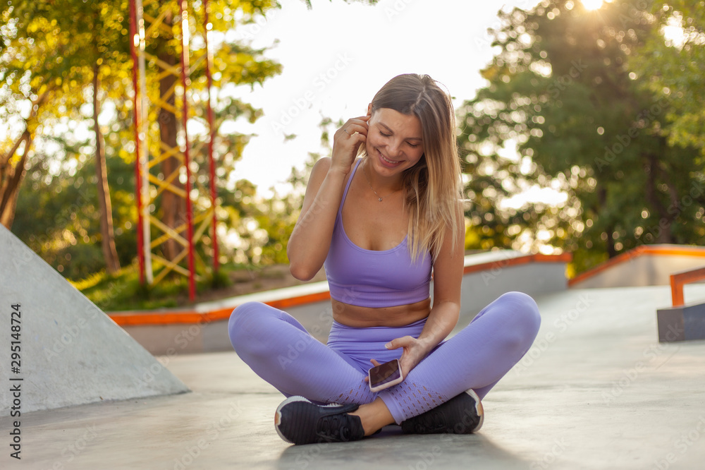 Young sport woman in sportswear is using a smartphone outdoors. Healthy lifestyle concept. Morning workout Young sport woman in sportswear is using a smartphone outdoors. Healthy lifestyle concept. Morning workout