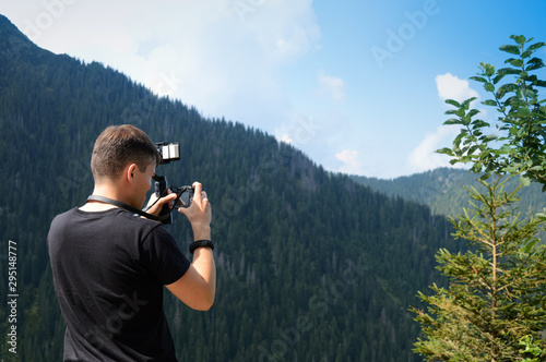 A young tourist in the mountains takes pictures and creates a video about the trip, the concept of light modern technologies for photographing travel and lifestyle, outdoor adventures