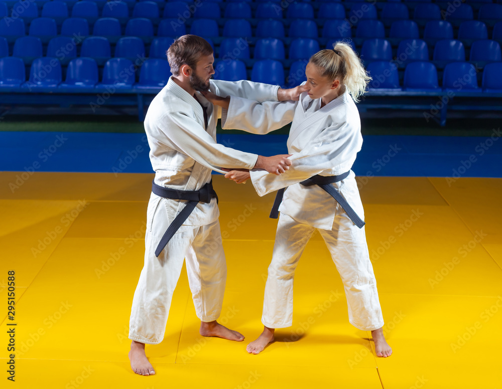 Martial arts. Sparing Portners. Sport man and woman in white kimono train judo captures in the sports hall Martial arts. Sparing Portners. Sport man and woman in white kimono train judo captures in the sports hall