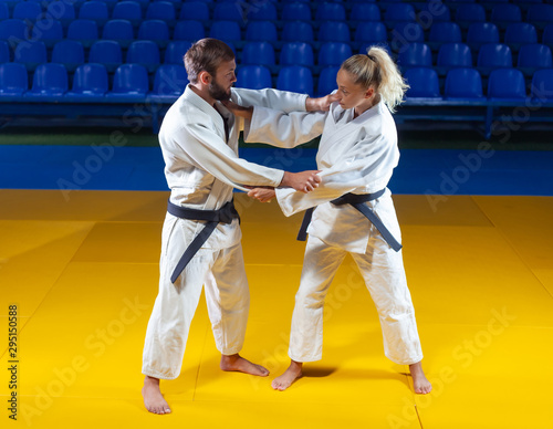 Martial arts. Sparing Portners. Sport man and woman in white kimono train judo captures in the sports hall