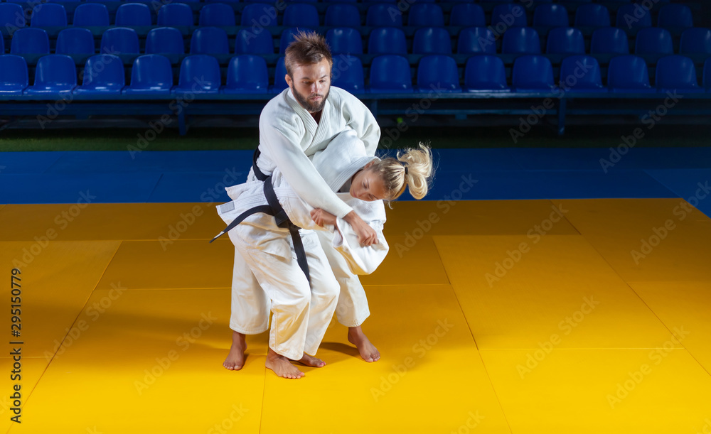 Martial arts. Sparing Portners. Sport man and woman in white kimono train judo throws and captures in the sports hall Martial arts. Sparing Portners. Sport man and woman in white kimono train judo throws and captures in the sports hall