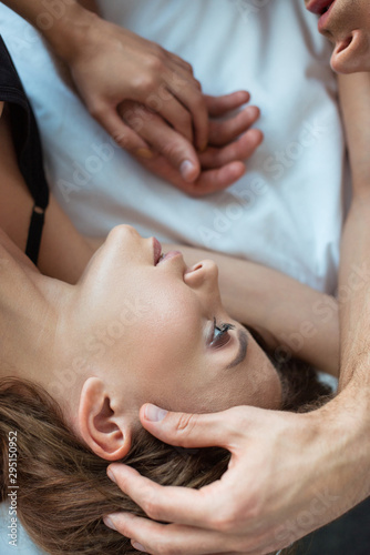 top view of man touching face of attractive girl while lying on bed