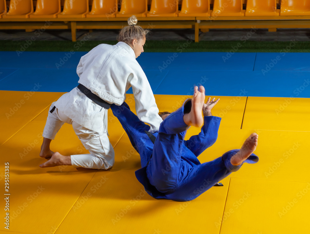 Martial arts. Sparing Portners. Sport man and woman in white and blue kimono train judo throws and captures in the sports hall Martial arts. Sparing Portners. Sport man and woman in white and blue kimono train judo throws and captures in the sports hall