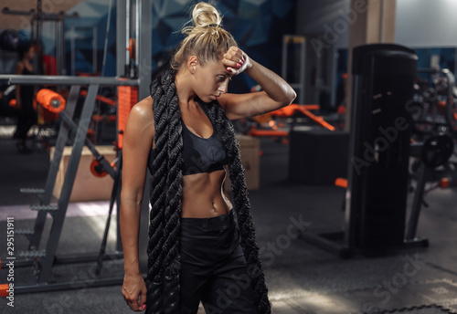 Tired sport woman in sportswear with battle rope on her neck in the gym. Functional training. Healthy lifestyle concept © splitov27