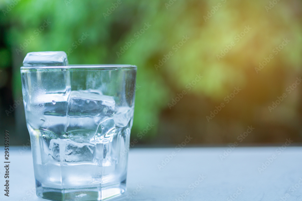 Glass with ice put on table green background of nature with copy space. Glass with ice put on table green background of nature with copy space.