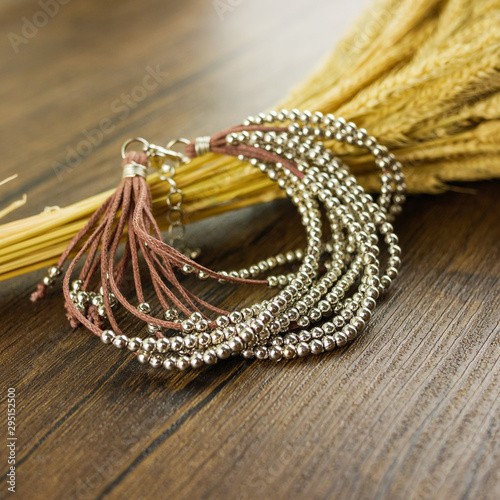 Brown multi strand bracelet on wooden background with dry grass 