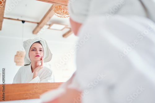 Image of beautiful woman in bathrobe and with towel on her head reflected in mirror