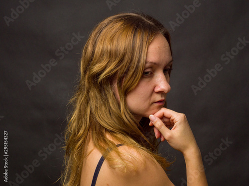 Portrait of young woman, no make up, low key, brown dark hair, no retouch making expressions