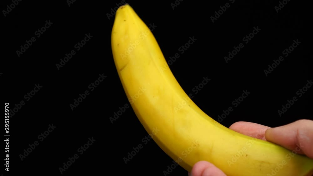 Male hand holds an banana on a black background Male hand holds an banana on a black background