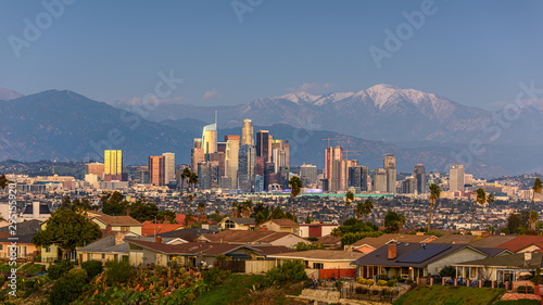 Downtown Los Angeles skyline with snow capped mountains behind at sunset