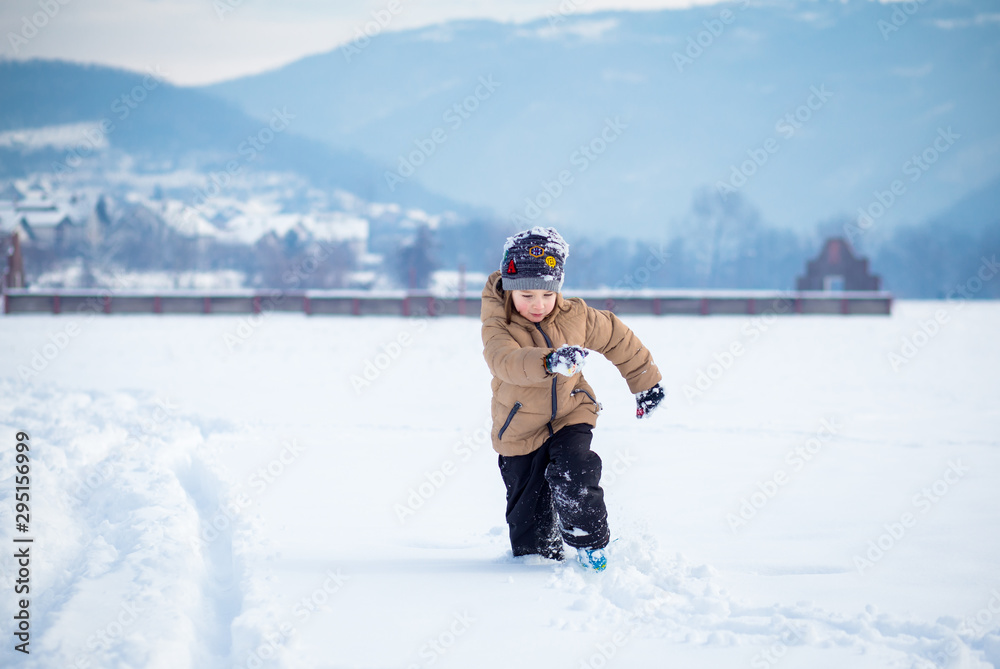 Boy having fun, playing outside, surrounded with snow.