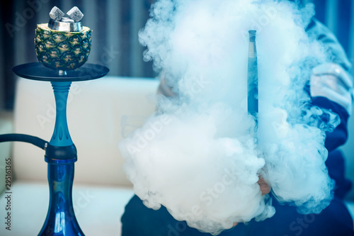 Fotografie Man holds hookah, hand in smoke shisha