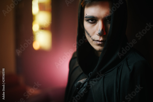 Close-up of a beautiful man's face with Halloween make-up. Young man in Halloween costume looking at the camera