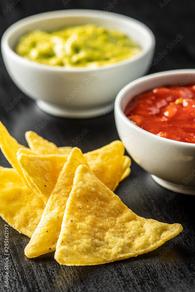 Corn nacho chips with avocado and tomato dip. Yellow tortilla chips and guacamole salsa. Corn nacho chips with avocado and tomato dip. Yellow tortilla chips and guacamole salsa.